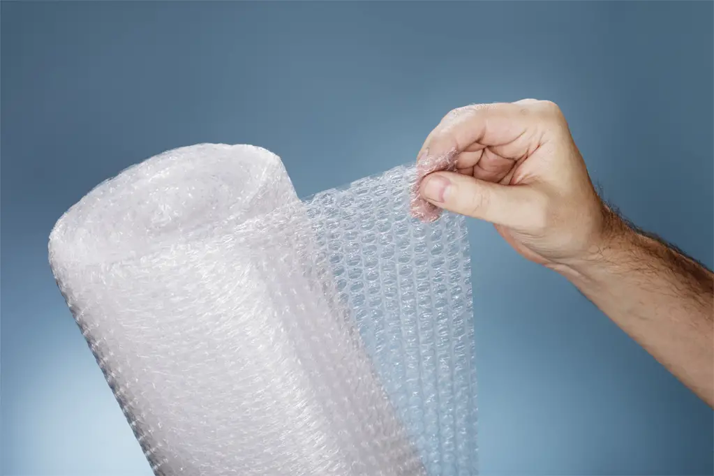 Man holding a roll of plastic bubble wrap.