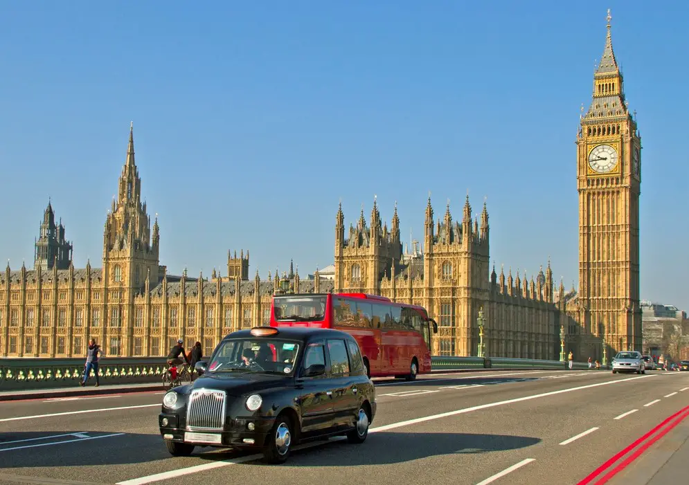 London black taxi in front of buildings of Parliament and Big Ben tower in London.